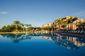 A hotel with a swimming pool, palm trees, and a clear blue sky. - Stylish and Contemporary Vista Cay Hideaway - Lake View 3bd/2ba #3vc4126 (Orlando)