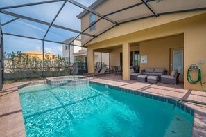 A swimming pool with a glass enclosure, outdoor seating, and a view of neighboring buildings. - Breathtaking Spacious Pool Home Near Disney. Star Wars Room! 7BD #7st485 (Davenport)