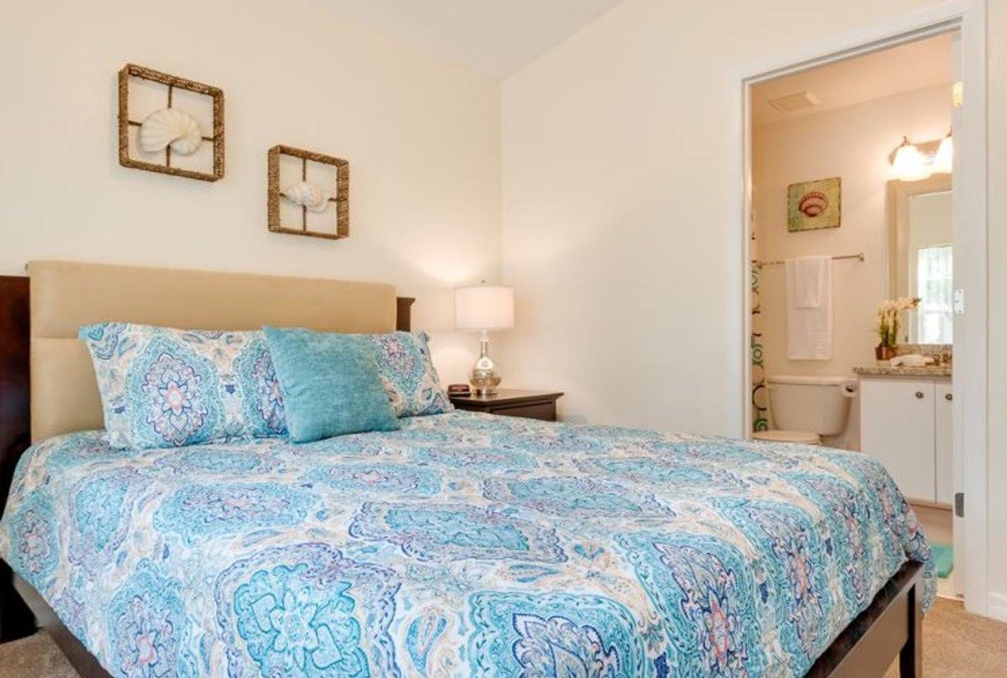 A bedroom with a bed, a nightstand, and a bathroom visible through an open door.