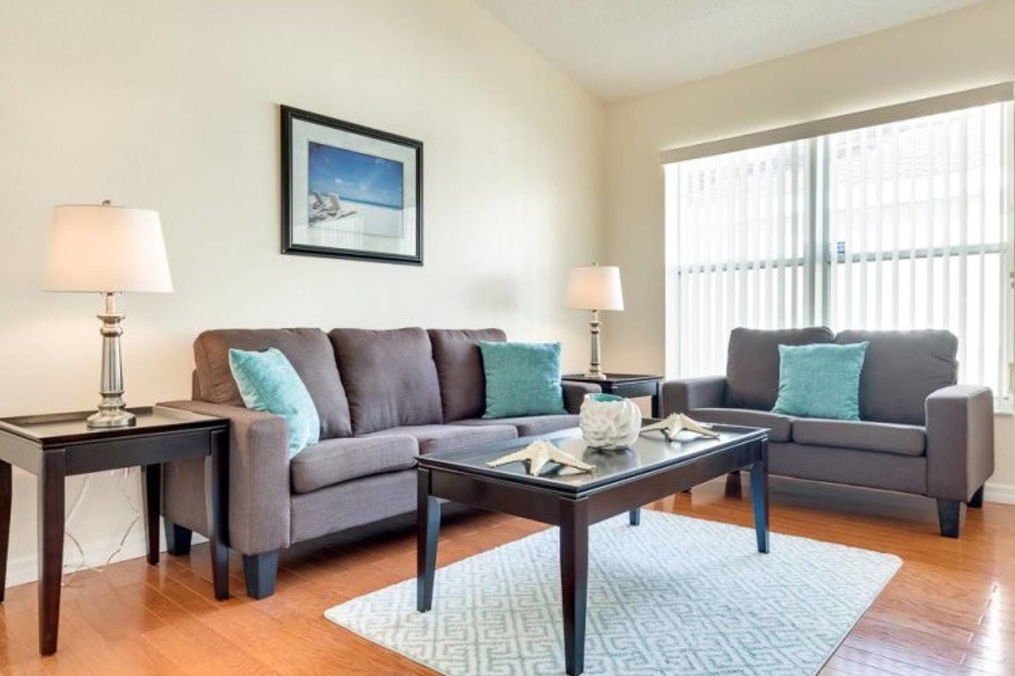 A living room with a sofa, two side tables, a coffee table, and a rug.