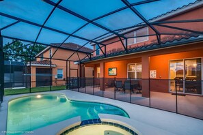 A residential property with a swimming pool, outdoor seating area, and a covered patio.