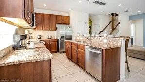 A modern kitchen with granite countertops, stainless steel appliances, wooden cabinets, and a built-in dishwasher.