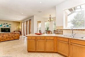 A spacious kitchen with wooden cabinets, a large island, and a view of the outdoors.