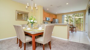 A dining area with a table set for four, a chandelier, and a view of the kitchen and balcony. - Perfect Orlando Home! Cozy and Contemporary 3bd/3.5ba Town Home - #3vc013 (Orlando)