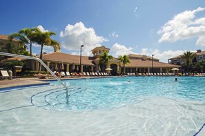 Una piscina con sillones de descanso y palmeras.