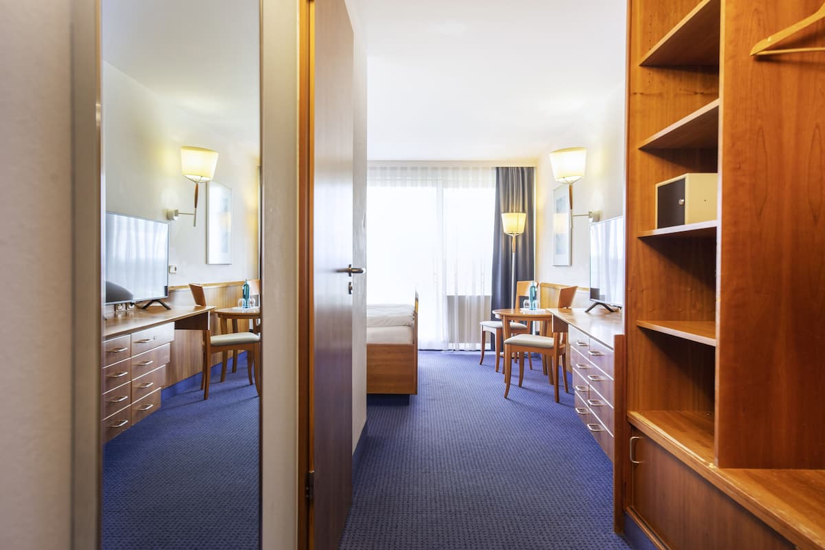 Une chambre d’hôtel comprenant un lit, un bureau, une chaise, une armoire et un miroir.