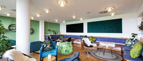 A modern lounge area with seating, a coffee table, and a large plant.