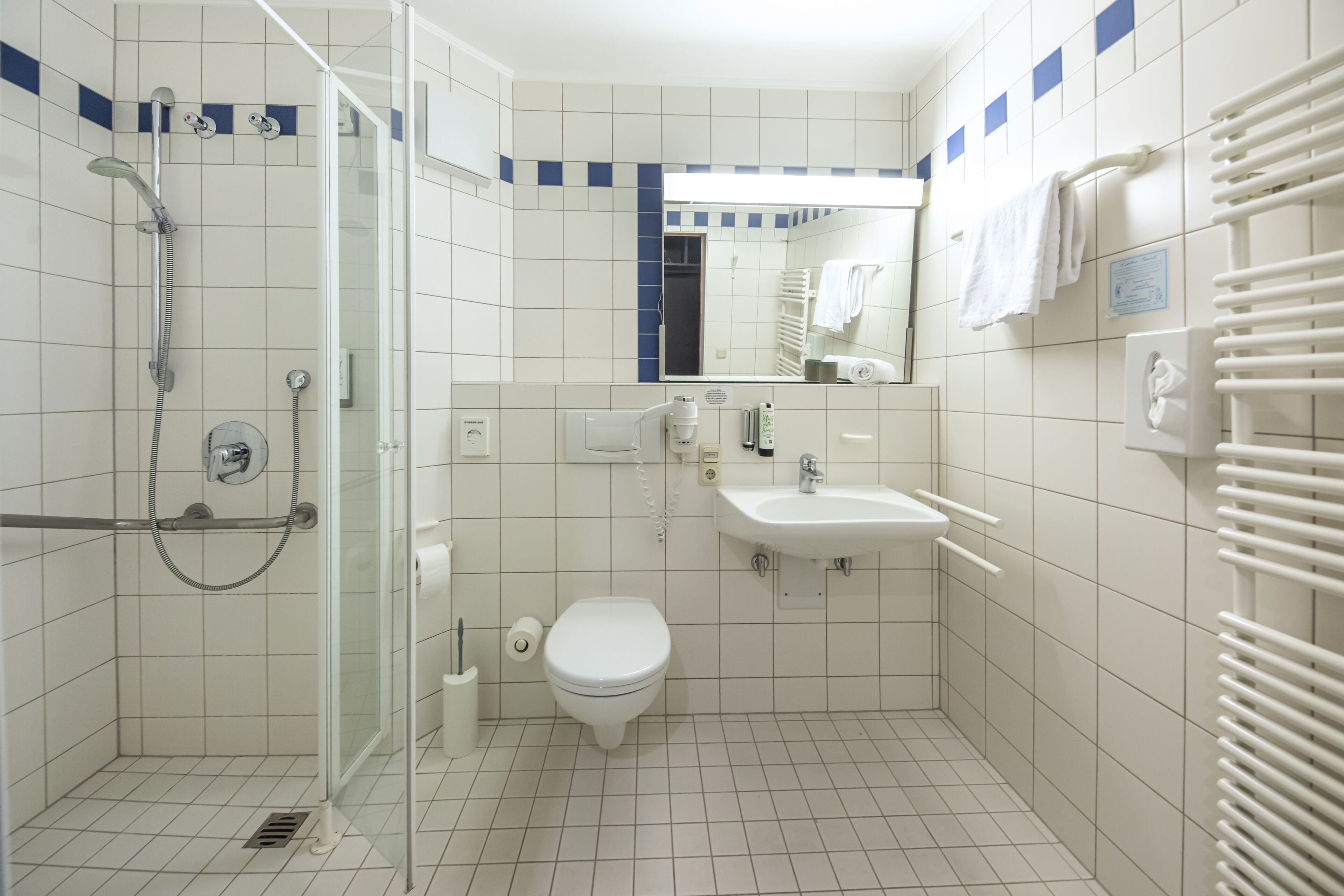 A small, clean bathroom with a toilet, sink, and shower.
