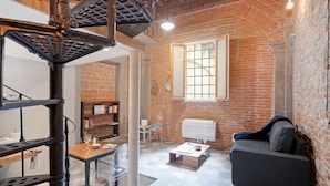 Un salon chaleureux avec un mur en briques, un canapé, une table basse et une bibliothèque.