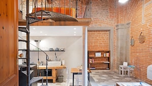 Un intérieur à plusieurs niveaux comprenant un escalier, un coin cuisine, un espace salon et une bibliothèque.