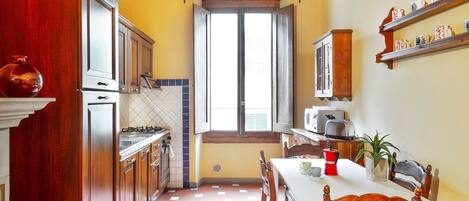 Una cocina compacta con armarios de madera, una ventana y un comedor con mesa y sillas.