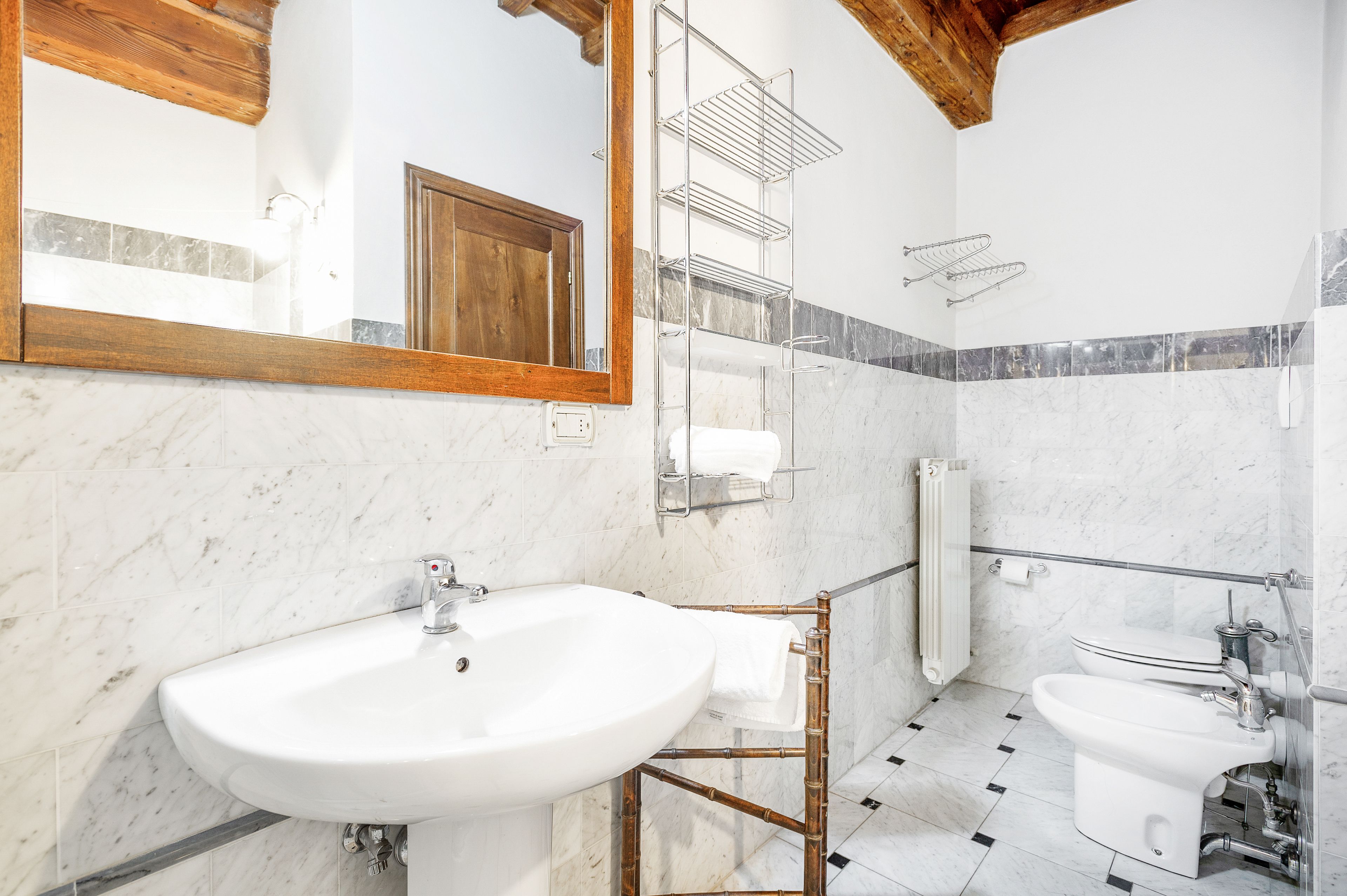 Un baño moderno con un espejo grande, un lavamanos, un bidé y un inodoro.