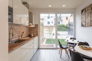 Een moderne keuken met een groot raam, een eethoek met een tafel en stoelen, en uitzicht op buiten.