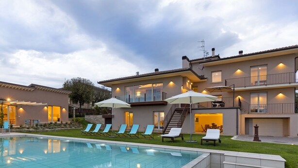 A modern two-story house with a swimming pool, outdoor seating, and a well-lit balcony. - Accommodation Spaccasole 2 on Cortona (Foiano della Chiana)