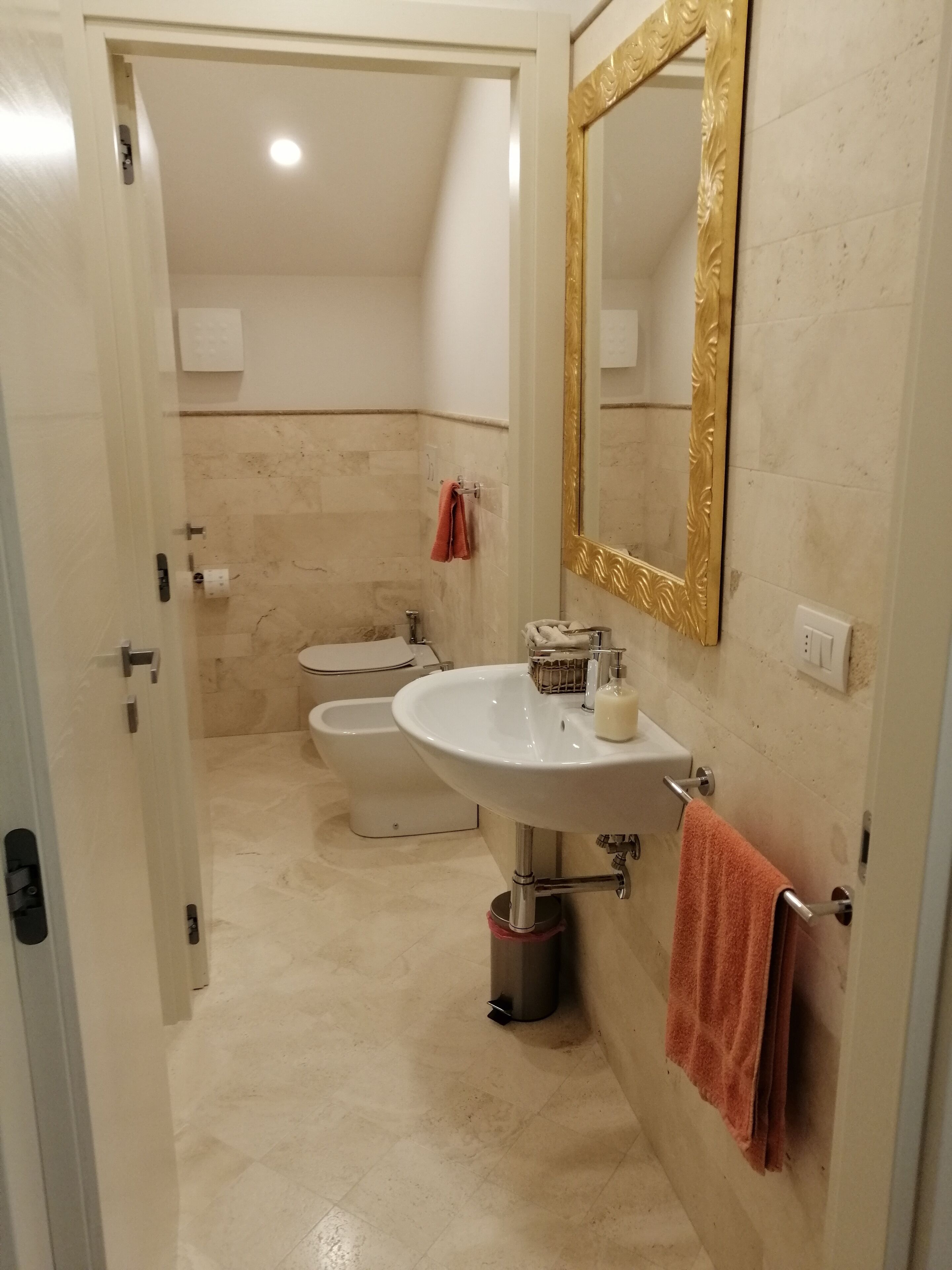 Un baño con lavamanos, espejo, toallero y bidé.