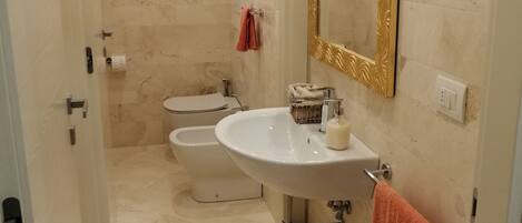 Un baño con lavamanos, espejo, toallero y bidé.