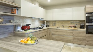 A modern kitchen with wooden cabinets, a built-in stove, and a fruit bowl on the counter. - Accommodation Spaccasole 2 on Cortona (Foiano della Chiana)