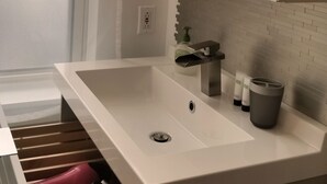 Un baño moderno con un lavamanos blanco, un espejo y un perchero para toallas.