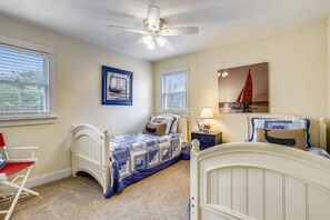Ein Schlafzimmer mit zwei Betten, einem Deckenventilator und Kunstwerken an den Wänden.