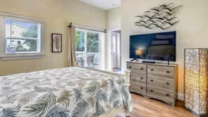 Ein Schlafzimmer mit einem Bett, einem Fernseher, einer Kommode und einem Fenster.