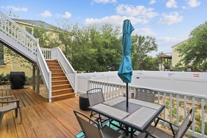 A wooden deck with a table and chairs, a covered patio area, and a white fence. - Pool and Hot Tub in Corolla! (Corolla)