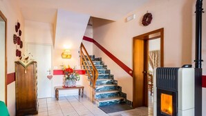 Una sala de estar con chimenea, una escalera y un banco lleno de flores.
