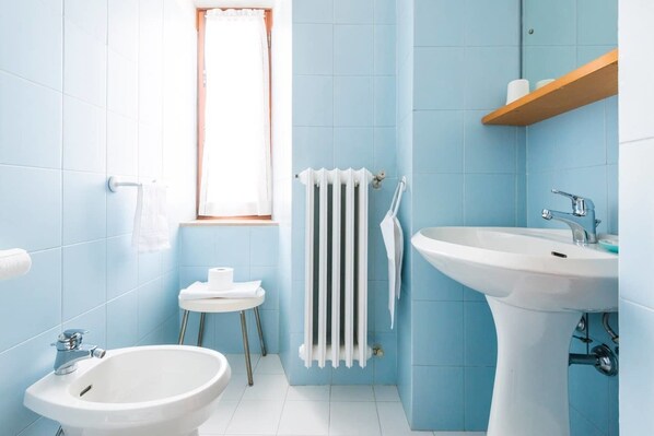 Un baño con bidé, lavamanos, ventana y radiador.