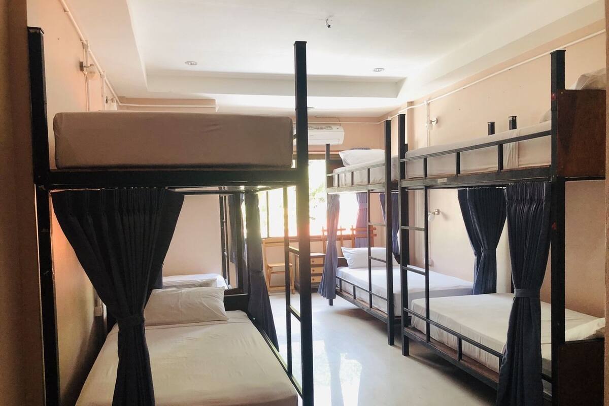 Un dormitorio con literas, una ventana con cortinas y un ventilador de techo.