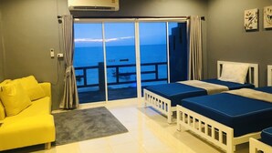 A hotel room with a balcony, a yellow sofa, two beds, and an air conditioning unit. - Koh Tao My Hostel (Koh Tao)