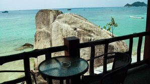 A view from a balcony overlooking turquoise waters with boats, a large rock formation, and a distant island. - Koh Tao My Hostel (Koh Tao)