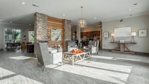 A spacious living area with a large brick fireplace, modern furniture, and a view into the kitchen. - ✪ Hidden Valley ✪ FREE Parking, Pool & Gym! (Ooltewah)