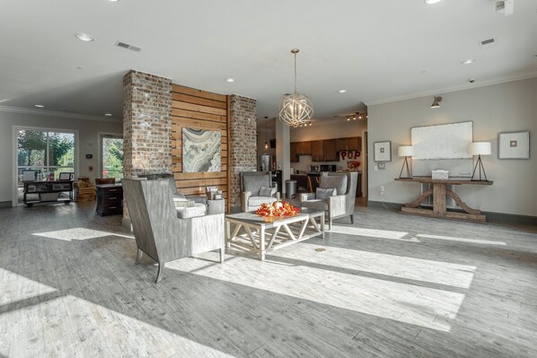 A spacious living area with a large brick fireplace, modern furniture, and a view into the kitchen.