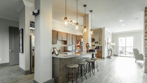A spacious kitchen with a central island, bar stools, pendant lighting, and a large window providing natural light. - ✪ Hidden Valley ✪ FREE Parking, Pool & Gym! (Ooltewah)