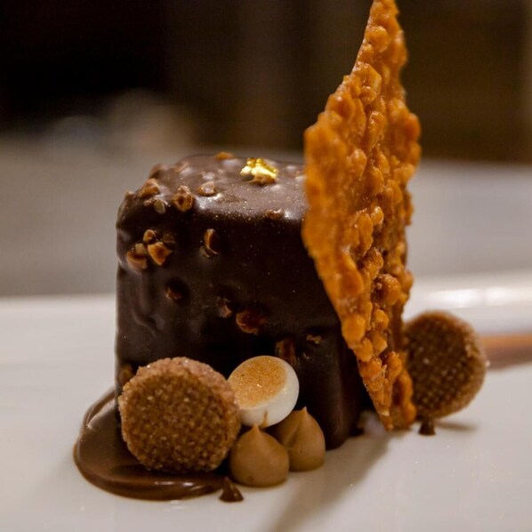 A dessert with a chocolate-covered item, a wafer, and round sweets on a white plate. - Hotel Snow Chill (Risoul)
