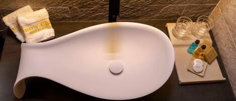 Ein modernes Waschbecken mit außergewöhnlichem Design, ein Handtuch und Toilettenartikel.