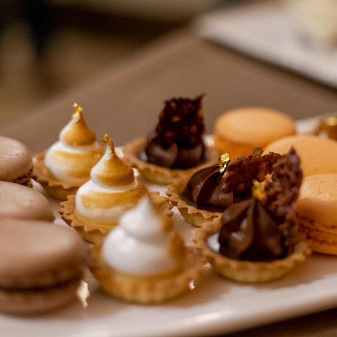 Une variété de desserts présentés sur une assiette, notamment des macarons et des tartes.