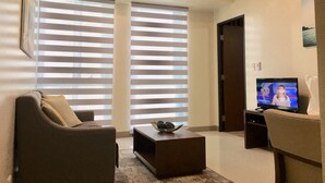 A modern living room with a sofa, a coffee table, and a television. - BGC One Uptown 1 Bedroom Corner Unit 16th floor with City View (Taguig)