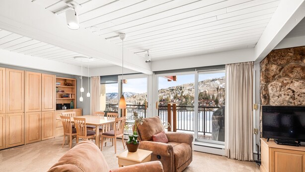 A spacious living area with a sofa, armchair, dining table, and TV. - Stonebridge Condos Ski-in/Ski-out via Elevator, 2 Bdrm, Den w/Murphy bed, 3 Bath #633 (Snowmass Village)