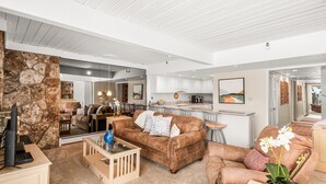 A spacious living room with a brown leather sofa, a coffee table, and a stone accent wall. - Stonebridge Condos Ski-in/Ski-out via Elevator, 2 Bdrm, Den w/Murphy bed, 3 Bath #633 (Snowmass Village)