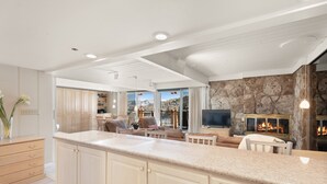 A spacious kitchen with a large island, wooden cabinets, and a stone fireplace. - Stonebridge Condos Ski-in/Ski-out via Elevator, 2 Bdrm, Den w/Murphy bed, 3 Bath #633 (Snowmass Village)