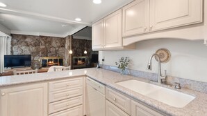 A modern kitchen with white cabinets, a granite countertop, a built-in dishwasher, and a stone backsplash. - Stonebridge Condos Ski-in/Ski-out via Elevator, 2 Bdrm, Den w/Murphy bed, 3 Bath #633 (Snowmass Village)