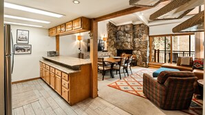 A kitchen with wooden cabinets, a stone wall, and a dining area with a fireplace. - 1 Bdrm and Loft, 2 BA Stonebridge Condo 727, Enclosed Loft & bonus room (Snowmass Village)