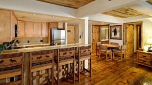 Una cocina amplia con armarios de madera, una isla central con taburetes de bar y un comedor con mesa y sillas de madera.