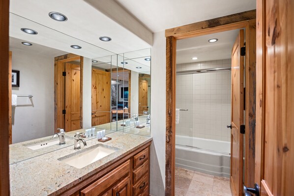 A bathroom with a wooden vanity, a large mirror, a sink, and a bathtub. - Great Location and Amenities 1 Bdrm, 1.5 BA Slopeside Stonebridge Condos 705 (Snowmass Village)