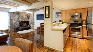 Una cocina moderna con armarios de madera, electrodomésticos de acero inoxidable y una chimenea de piedra en la sala de estar.