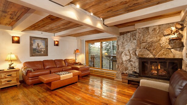 Una sala de estar acogedora con chimenea de piedra, vigas de madera y un sofá de cuero.