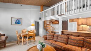 Un'ampia zona giorno con un tavolo da pranzo in legno, un divano e una scala che conduce a un piano superiore.