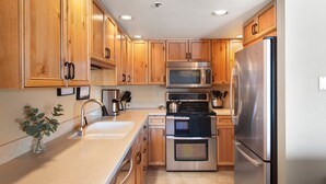 Una cocina moderna con armarios de madera, electrodomésticos de acero inoxidable y un lavamanos.