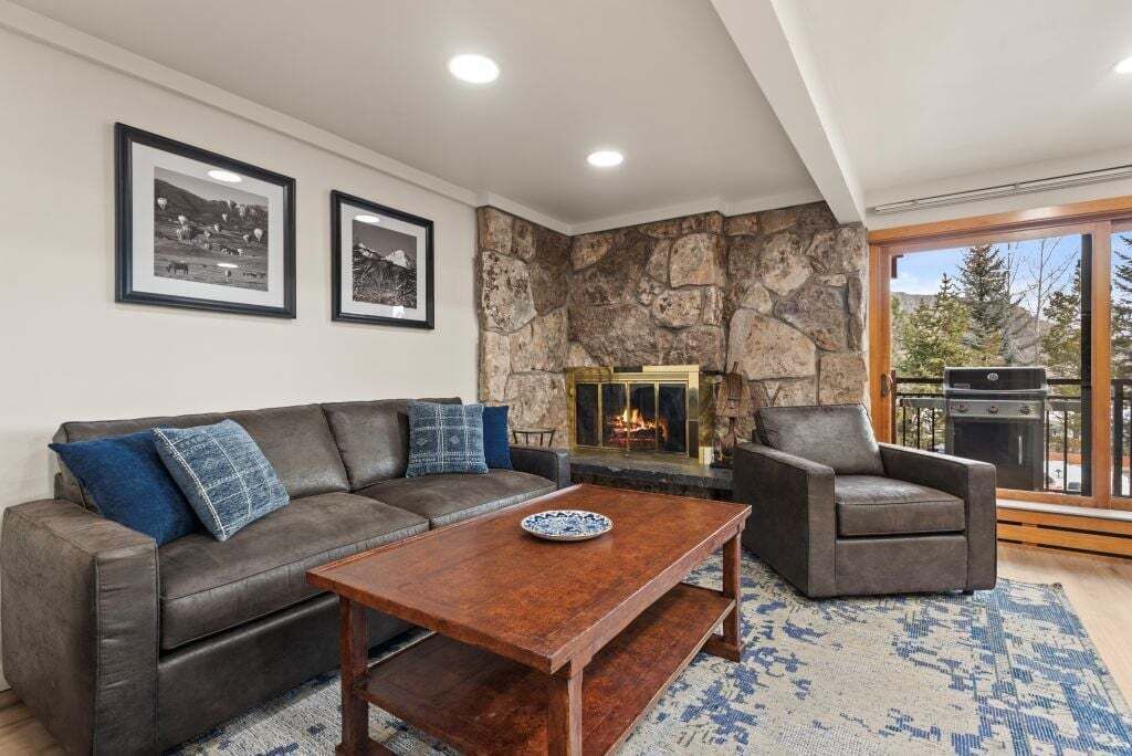 A living room with a stone fireplace, a sofa, a coffee table, and a chair.