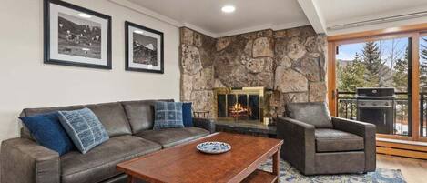 A living room with a stone fireplace, a sofa, a coffee table, and a chair.